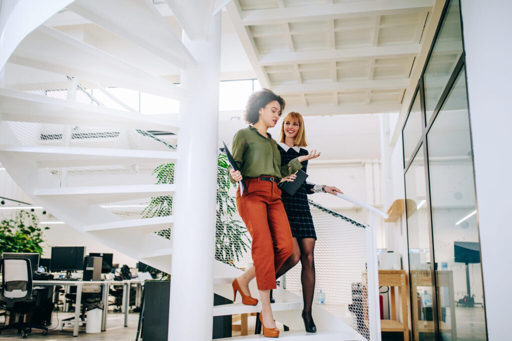 shot of millennial and Gen Z women walking down the stairs talking