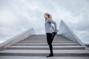 Side view of young female stretching her leg. Fitness woman warming up before jogging.