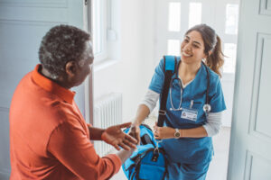 Nurse visiting mature patient at home. She is holding bag and entering at patient's home.