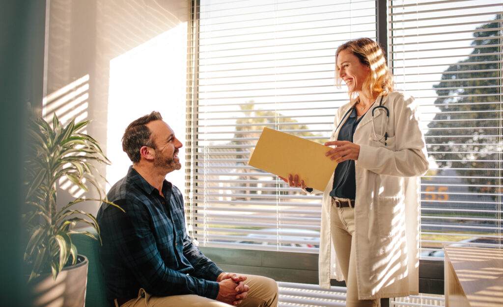 Female doctor talking to male patient in a primary care appointment.