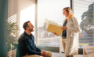Female doctor talking to male patient in a primary care appointment.
